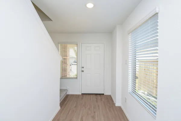 a view of an empty room with wooden floor and a window