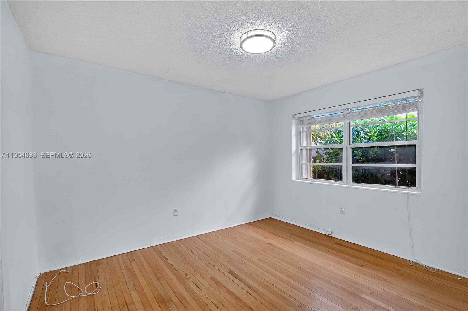 2399 Southwest 26th Lane Miami, FL 33133 - Photo 16 of 39 a view of an empty room with wooden floor and a window