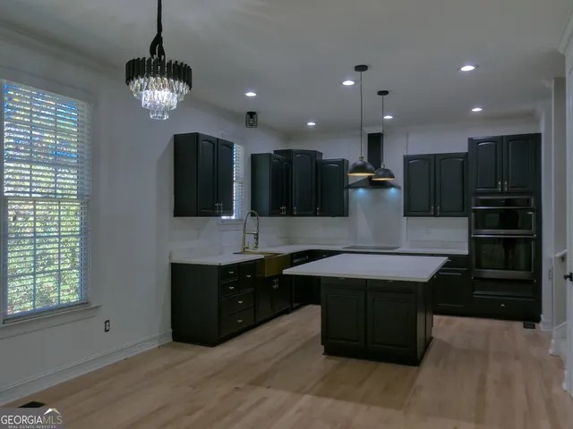 a large kitchen with kitchen island a sink dishwasher a stove and a refrigerator with wooden floor