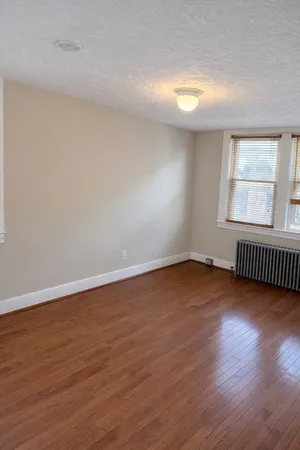 a view of an empty room with wooden floor and window