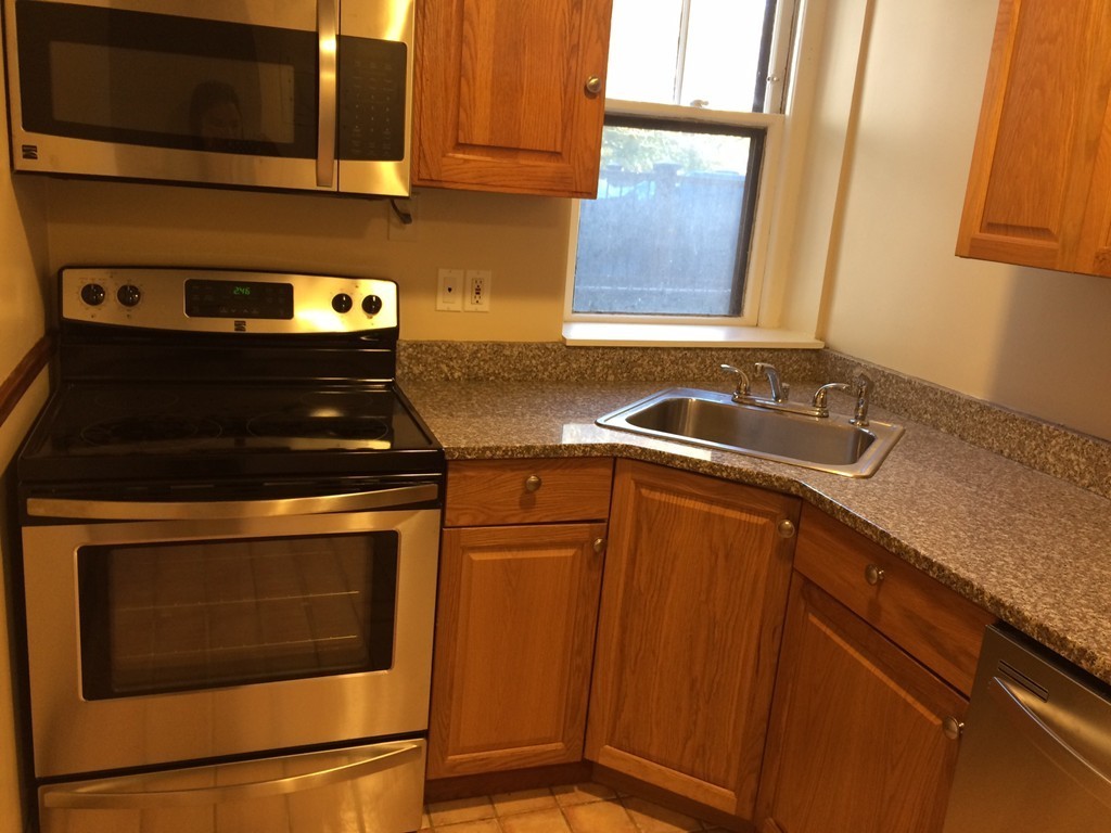 149 Winthrop Road, Unit 1 Brookline, MA 02445 - Photo 3 of 21 a kitchen with granite countertop wood cabinets and a stove top oven
