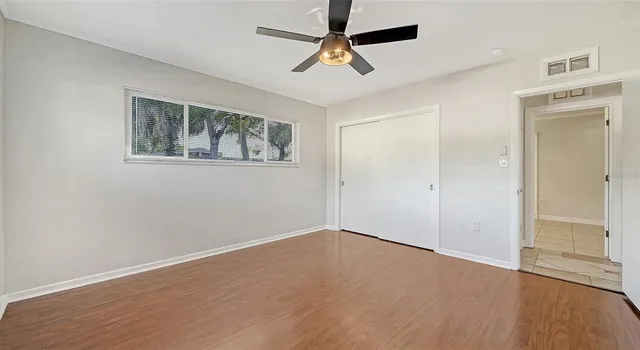 a view of an empty room with window and wooden floor