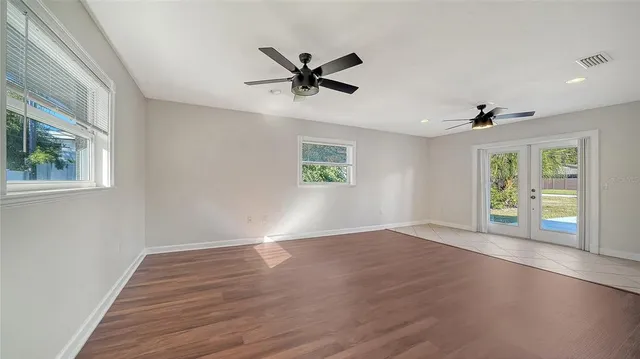 a view of an empty room with window and wooden floor