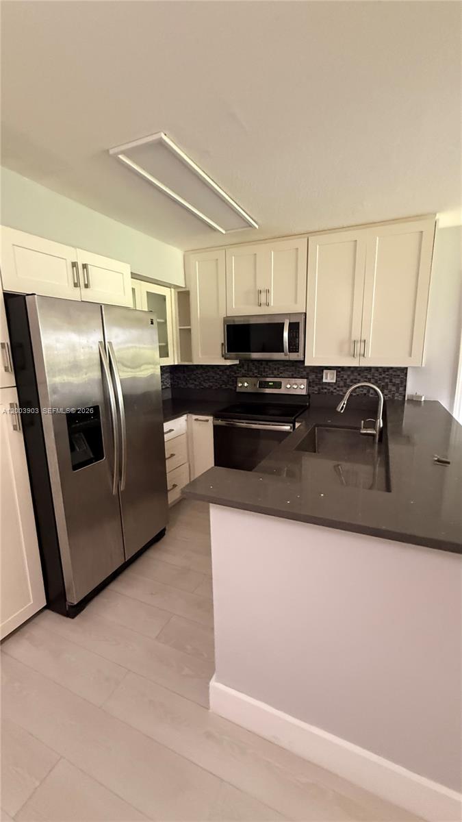 821 Lyons Road, Unit 21102 Coconut Creek, FL 33063 - Photo 12 of 17 a kitchen with stainless steel appliances granite countertop a sink a stove a microwave a refrigerator a counter space and cabinets