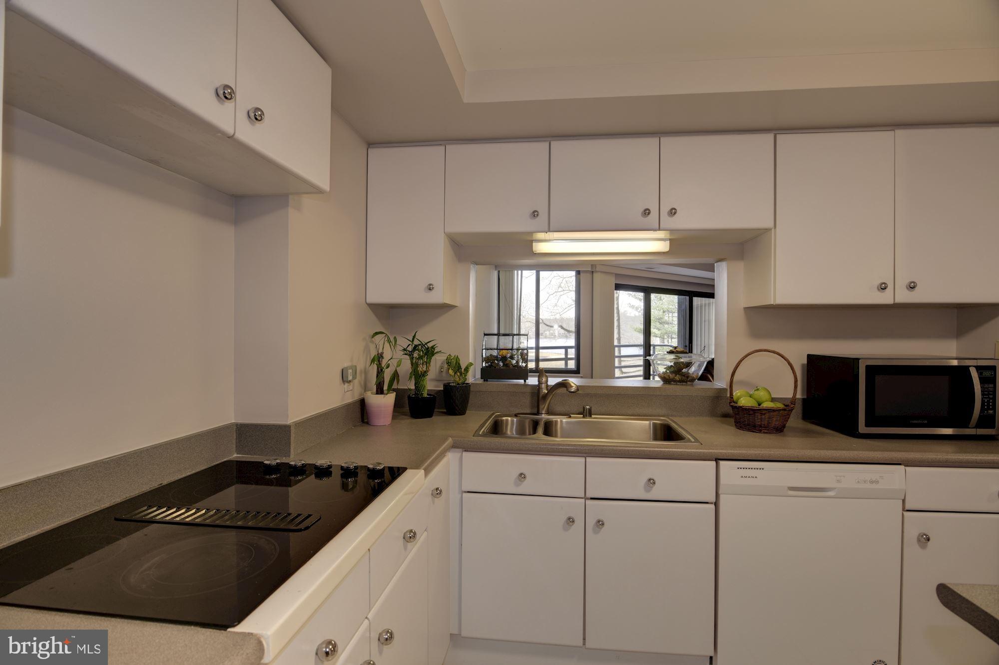 10001 Windstream Drive, Unit 404 Columbia, MD 21044 - Photo 8 of 29 a kitchen with a sink dishwasher a stove and a microwave oven on cabinets