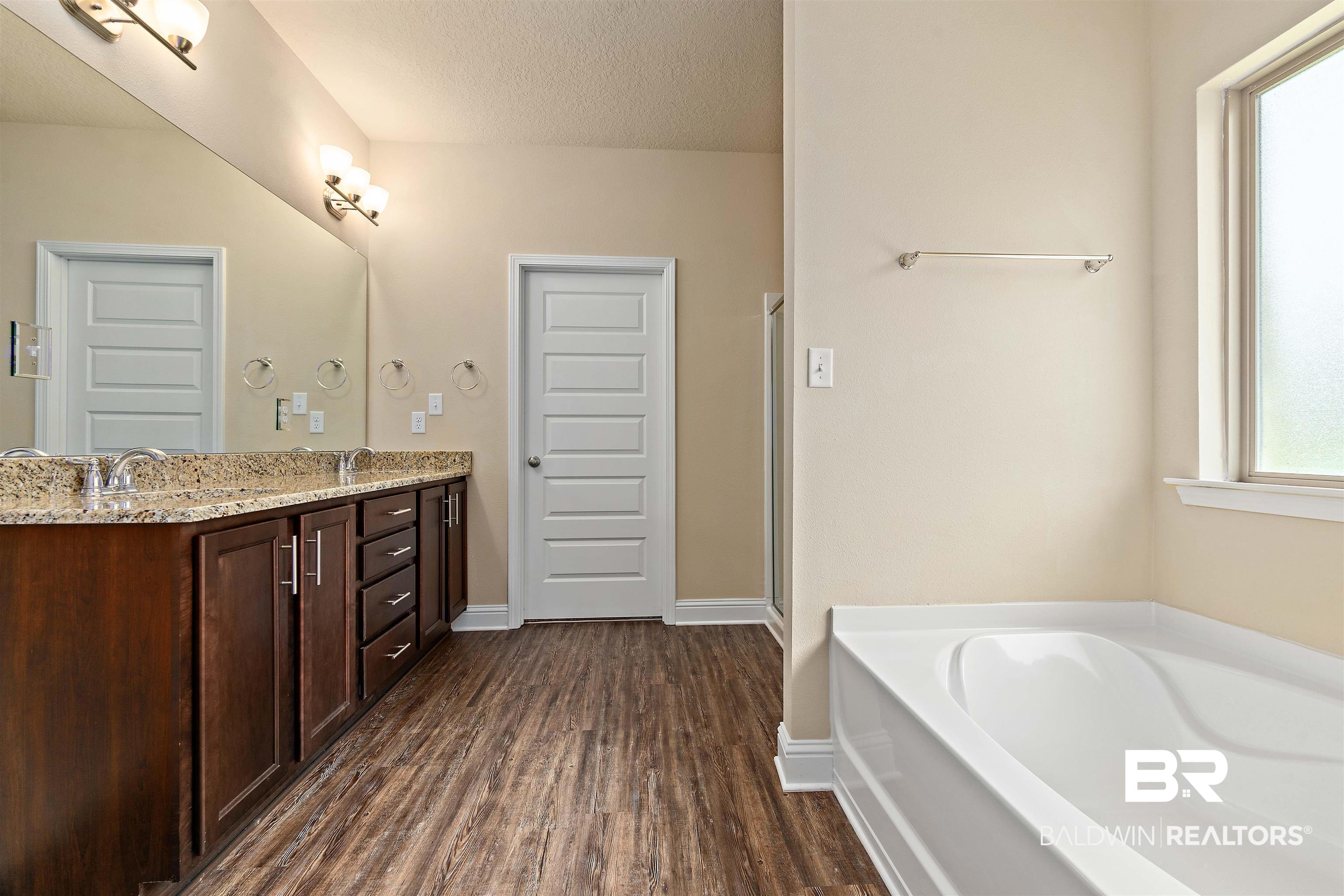 1864 Gwin Court Mobile, AL 36695 - Photo 23 of 37 Bathroom featuring a washtub, hardwood / wood-style floors, a textured ceiling, and vanity