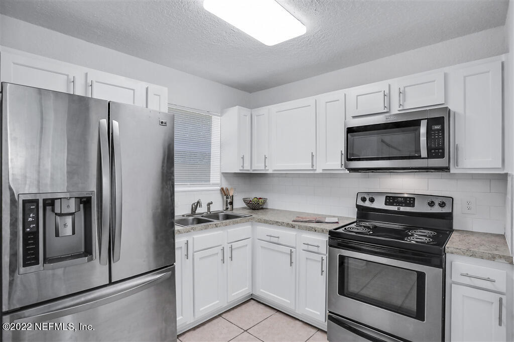 4657 Colchester Road Jacksonville, FL 32208 - Photo 9 of 23 a kitchen with stainless steel appliances a refrigerator stove and microwave