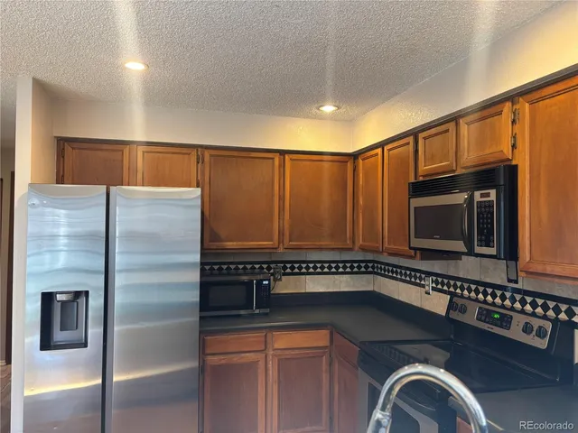 a kitchen with stainless steel appliances granite countertop a refrigerator a stove a sink and dishwasher