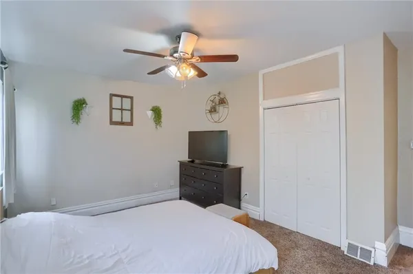 a bedroom with a bed and a flat tv screen on dresser