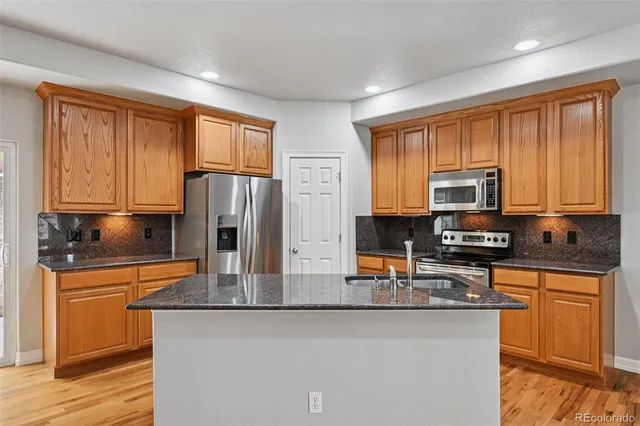 a kitchen with granite countertop wood cabinets and stainless steel appliances