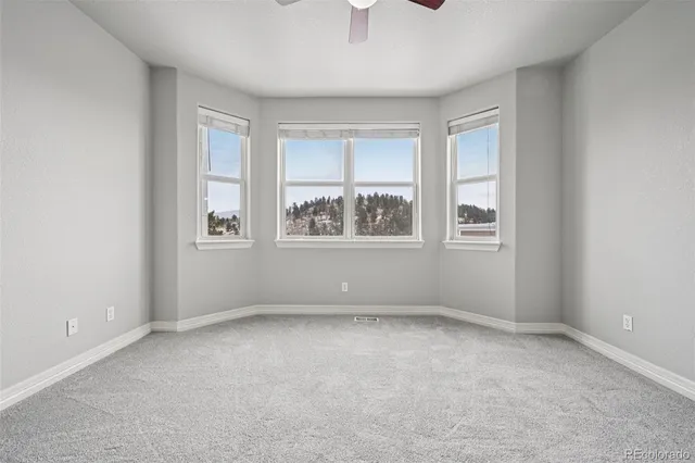 an empty room with chandelier fan and windows
