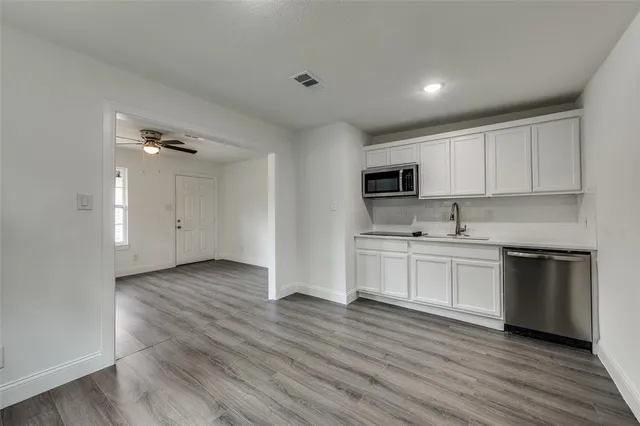 a kitchen with granite countertop white cabinets and black stainless steel appliances