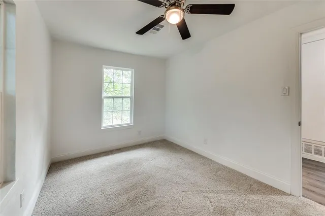 an empty room with a window and a fan