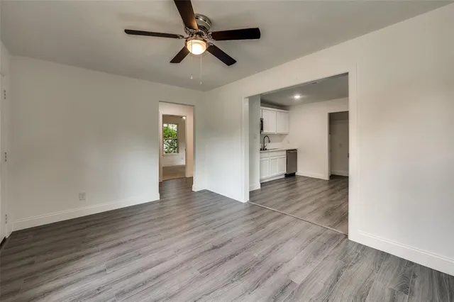 a view of an empty room with wooden floor and a ceiling fan
