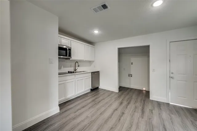 a kitchen with granite countertop a sink cabinets and wooden floor