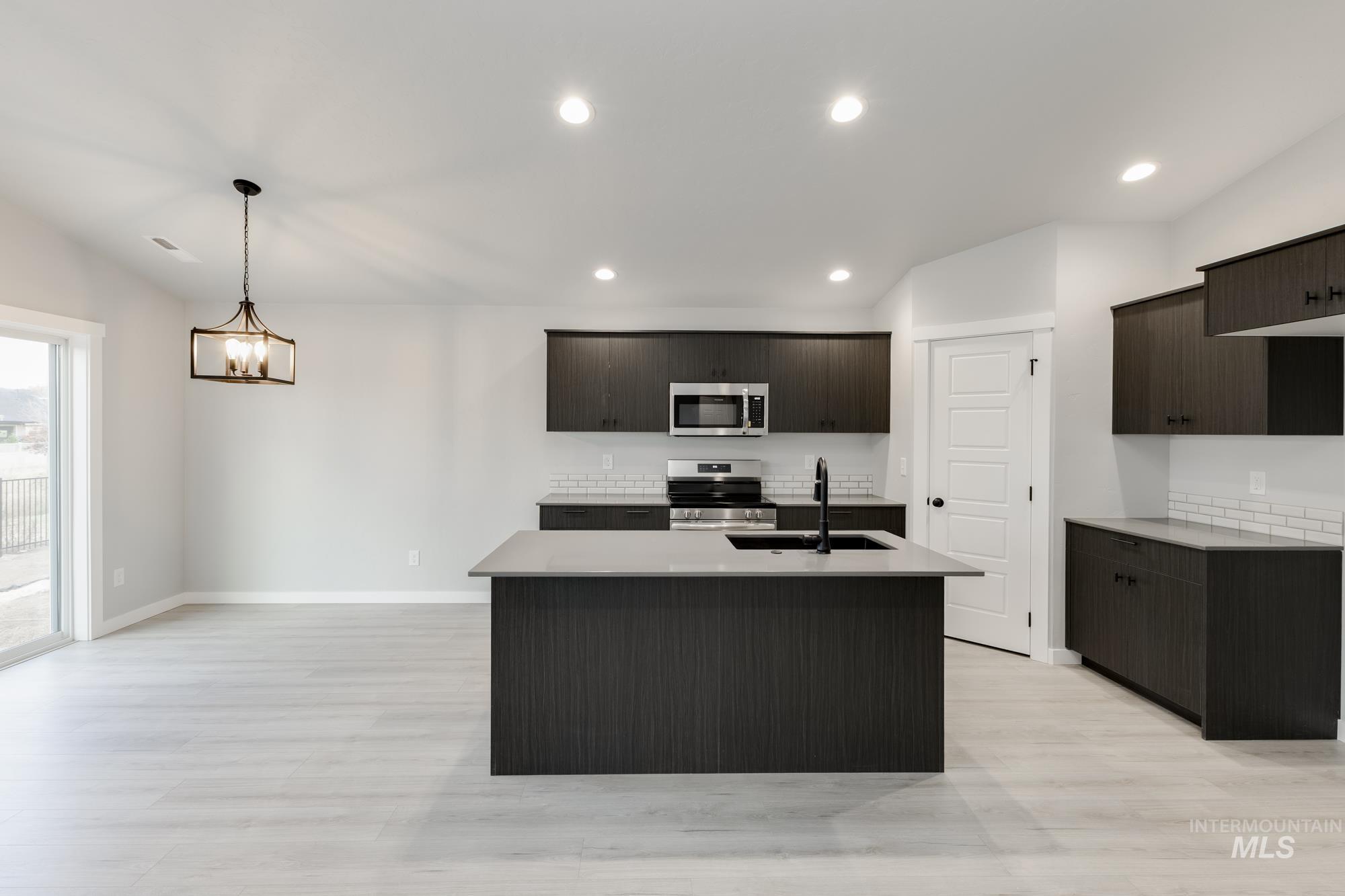 931 North Aleppo Way Meridian, ID 83642 - Photo 3 of 20 Kitchen featuring stainless steel appliances, an island with sink, recessed lighting, light wood-style flooring, and hanging light fixtures