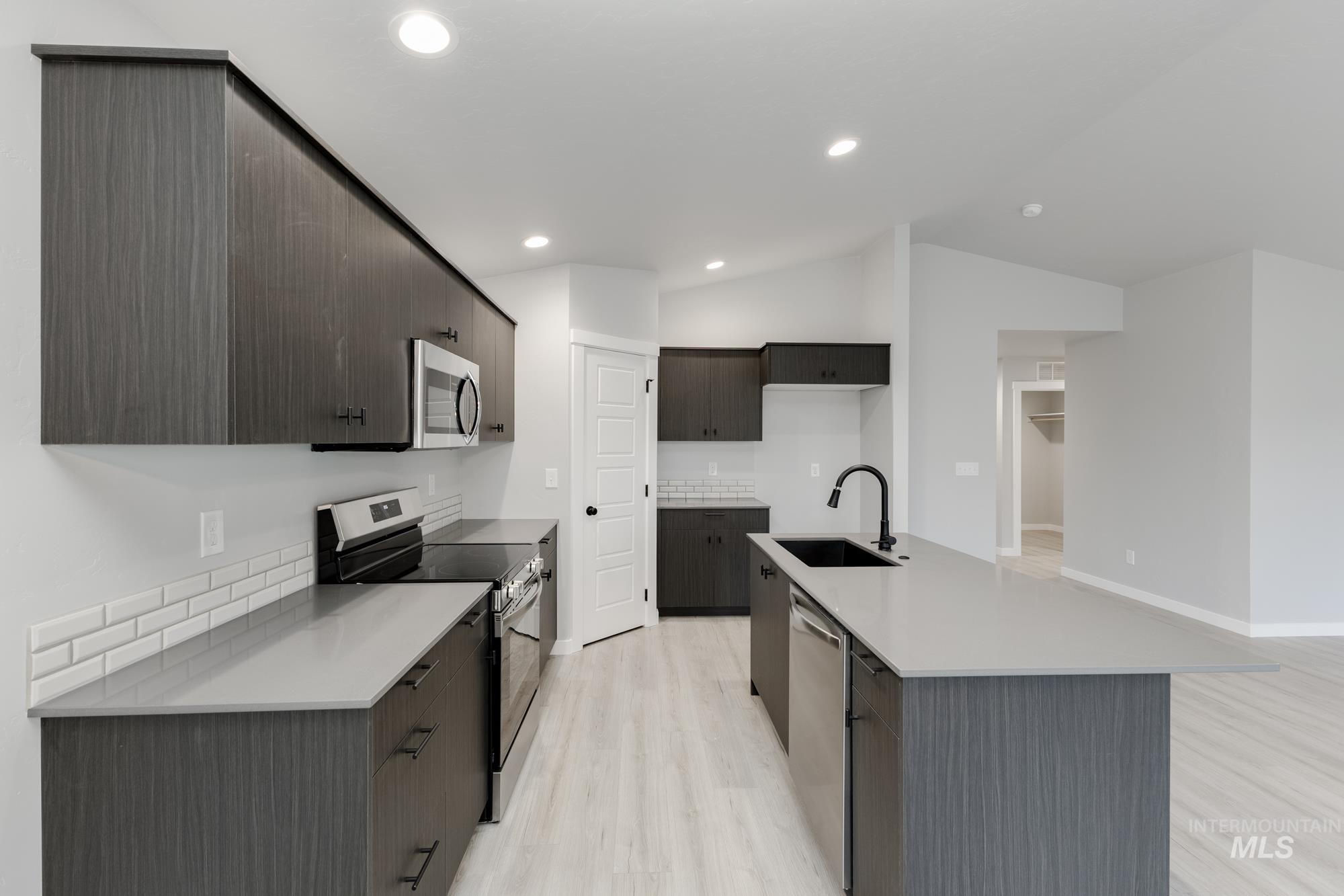 931 North Aleppo Way Meridian, ID 83642 - Photo 5 of 20 Kitchen with appliances with stainless steel finishes, light wood-type flooring, vaulted ceiling, modern cabinets, and a center island with sink