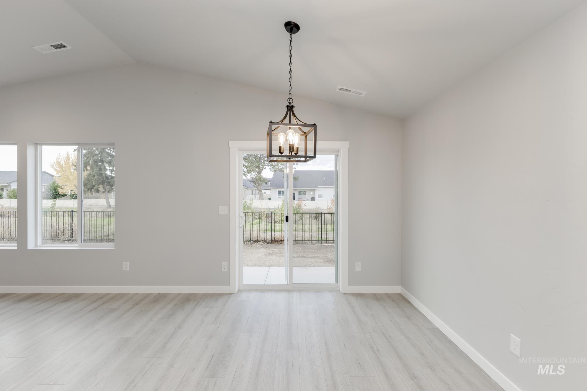 931 North Aleppo Way Meridian, ID 83642 - Photo 6 of 20 Unfurnished dining area with light wood-style flooring, lofted ceiling, and a chandelier
