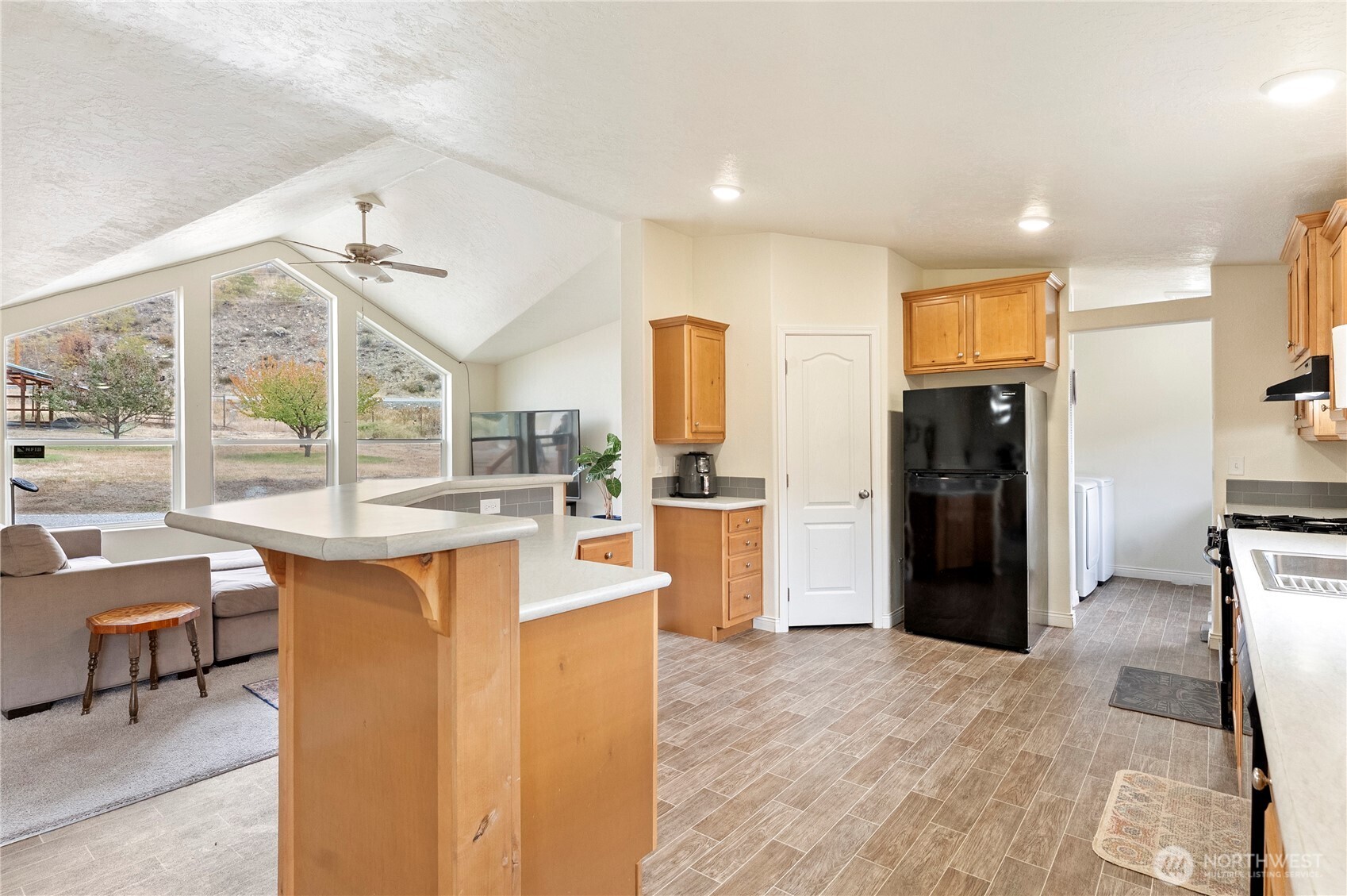 2431 Highway 153 Twisp, WA 98856 - Photo 11 of 40 a kitchen with stainless steel appliances kitchen island granite countertop a refrigerator a stove a sink a dining table and chairs with wooden floor