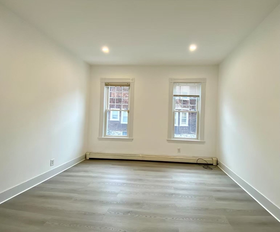 18 Howard Street, Unit 1 Waltham, MA 02451 - Photo 4 of 12 an empty room with wooden floor and windows
