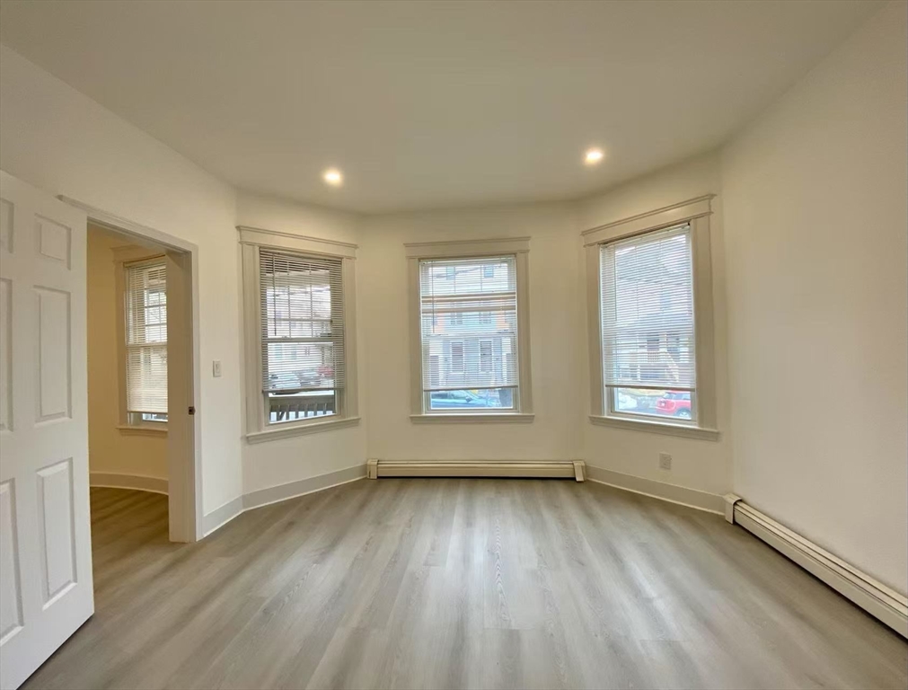 18 Howard Street, Unit 1 Waltham, MA 02451 - Photo 5 of 12 a view of an empty room with wooden floor and a window
