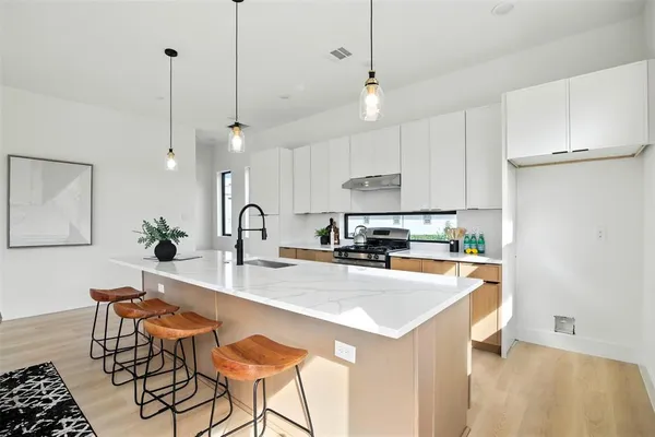 a kitchen with stainless steel appliances kitchen island a table chairs and a refrigerator