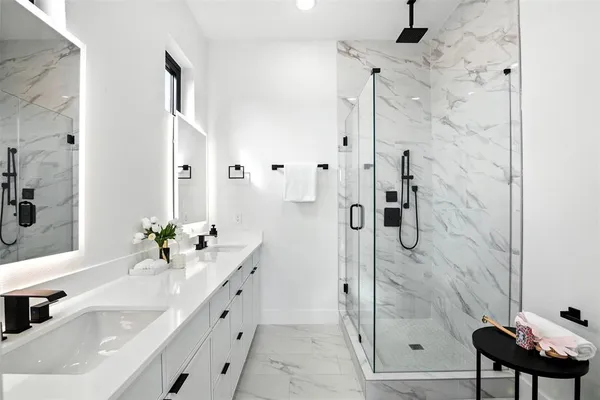 a bathroom with a double vanity sink mirror and shower