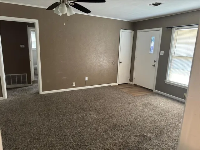 an empty room with windows and chandelier fan