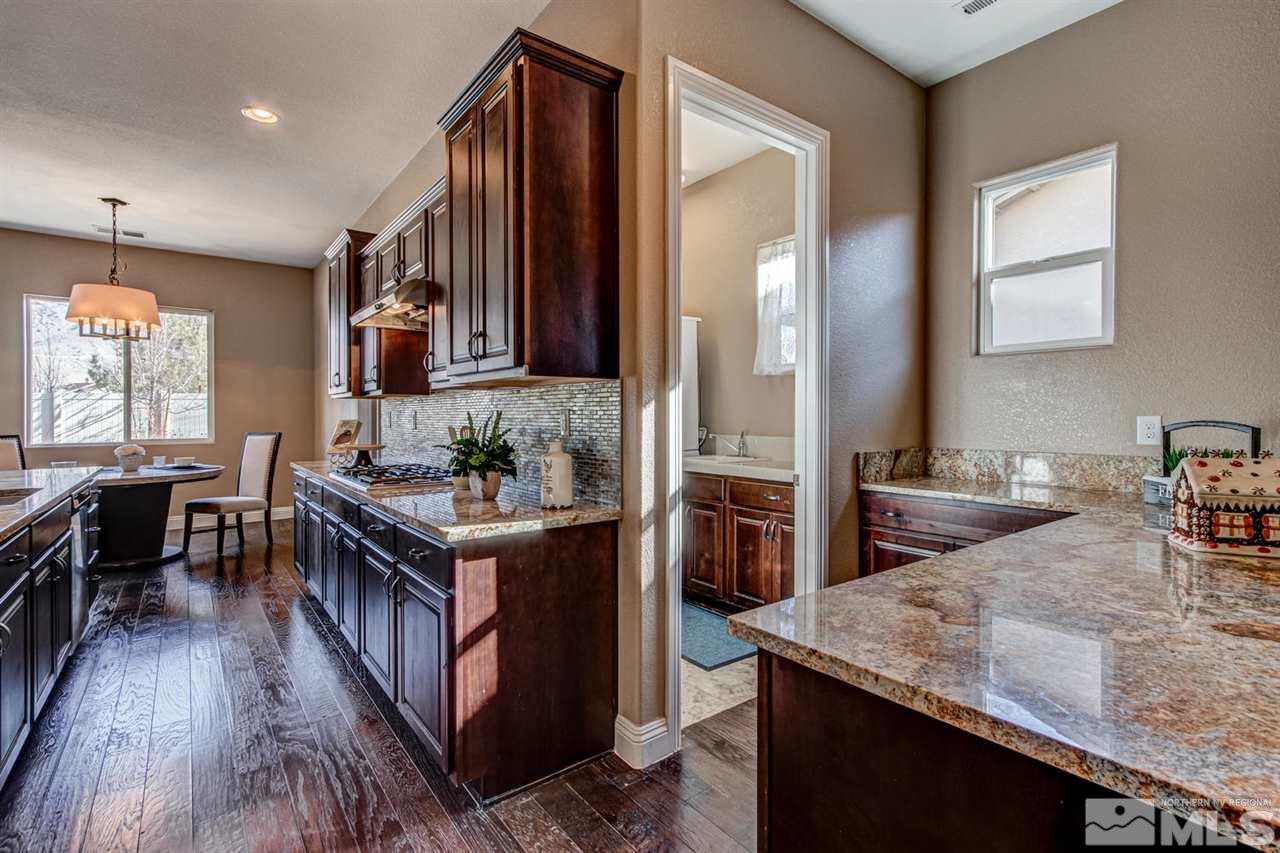 10060 Gold Cup Lane Reno, NV 89521 - Photo 12 of 25 a kitchen with granite countertop a table chairs sink and cabinets