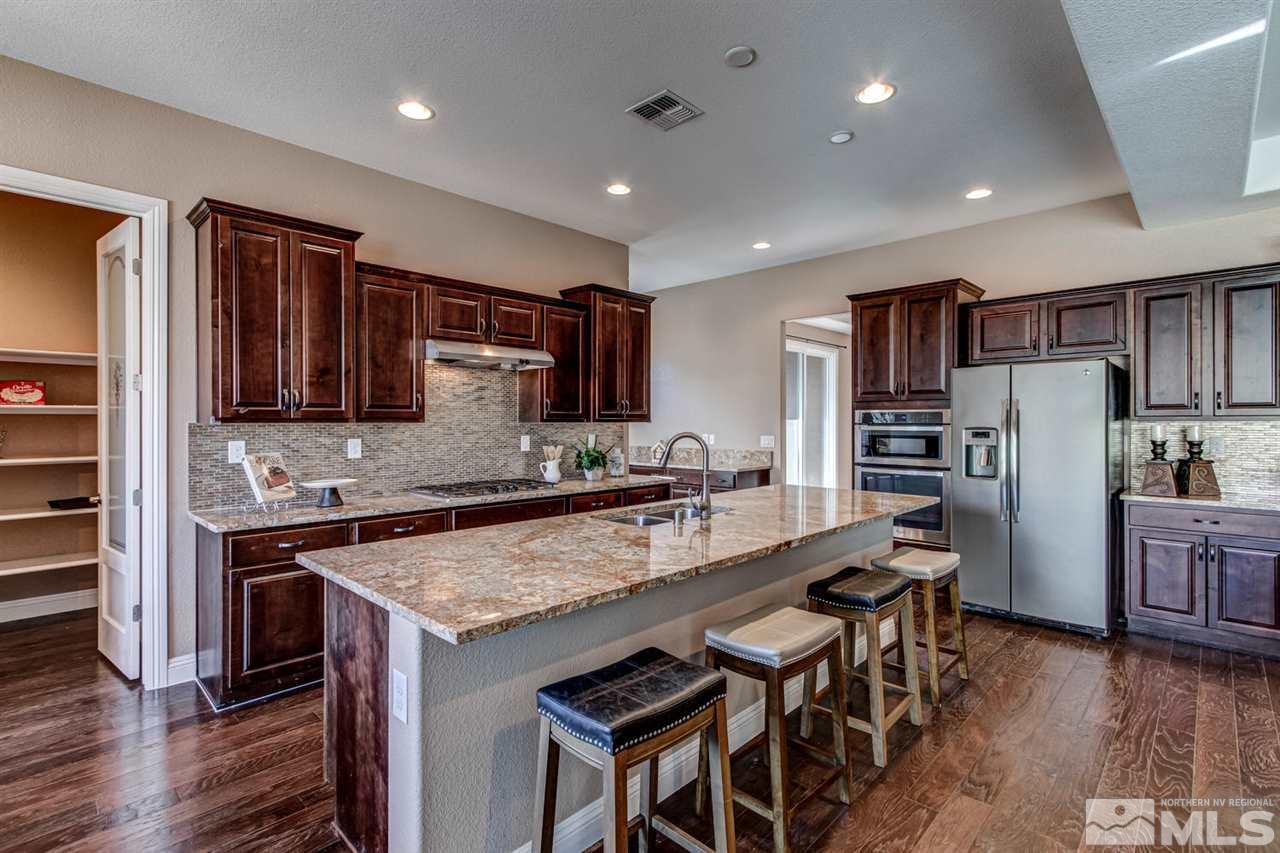 10060 Gold Cup Lane Reno, NV 89521 - Photo 10 of 25 a kitchen with refrigerator a sink wooden cabinets and chairs