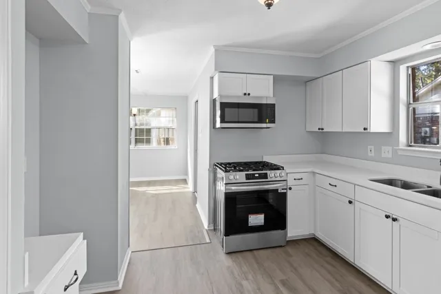 a kitchen with cabinets stainless steel appliances a sink and wooden floor