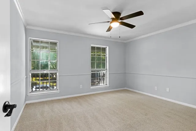 an empty room with ceiling fan and windows