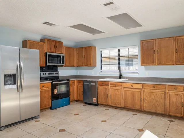a large kitchen with granite countertop cabinets stainless steel appliances a window and a sink