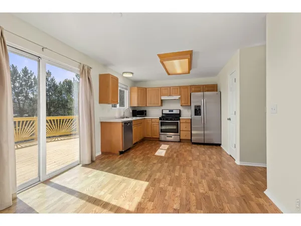 a view of a kitchen with wooden floor electronic appliances and windows