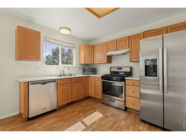 a kitchen with granite countertop a sink cabinets stainless steel appliances and a window