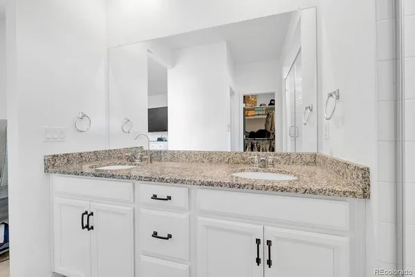 a bathroom with a granite countertop sink and white cabinets