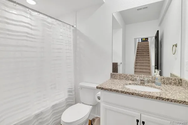 a bathroom with a granite countertop sink toilet and shower