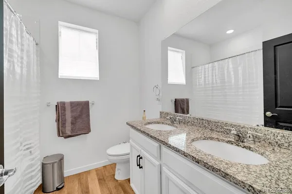 a bathroom with a granite countertop double vanity sink and a mirror