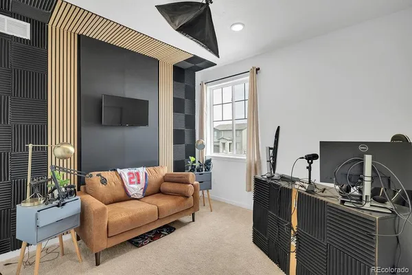 a living room with furniture a flat screen tv and a refrigerator