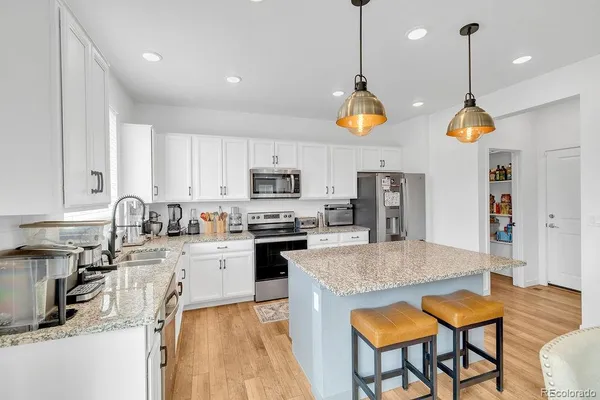 a kitchen with stainless steel appliances granite countertop a stove top oven a sink a dining table and chairs