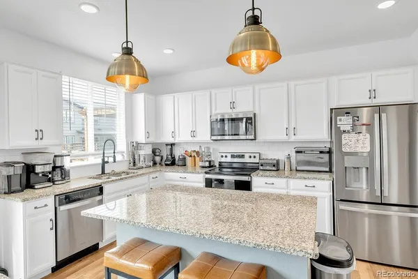 a kitchen with stainless steel appliances granite countertop a sink a stove a refrigerator and cabinets