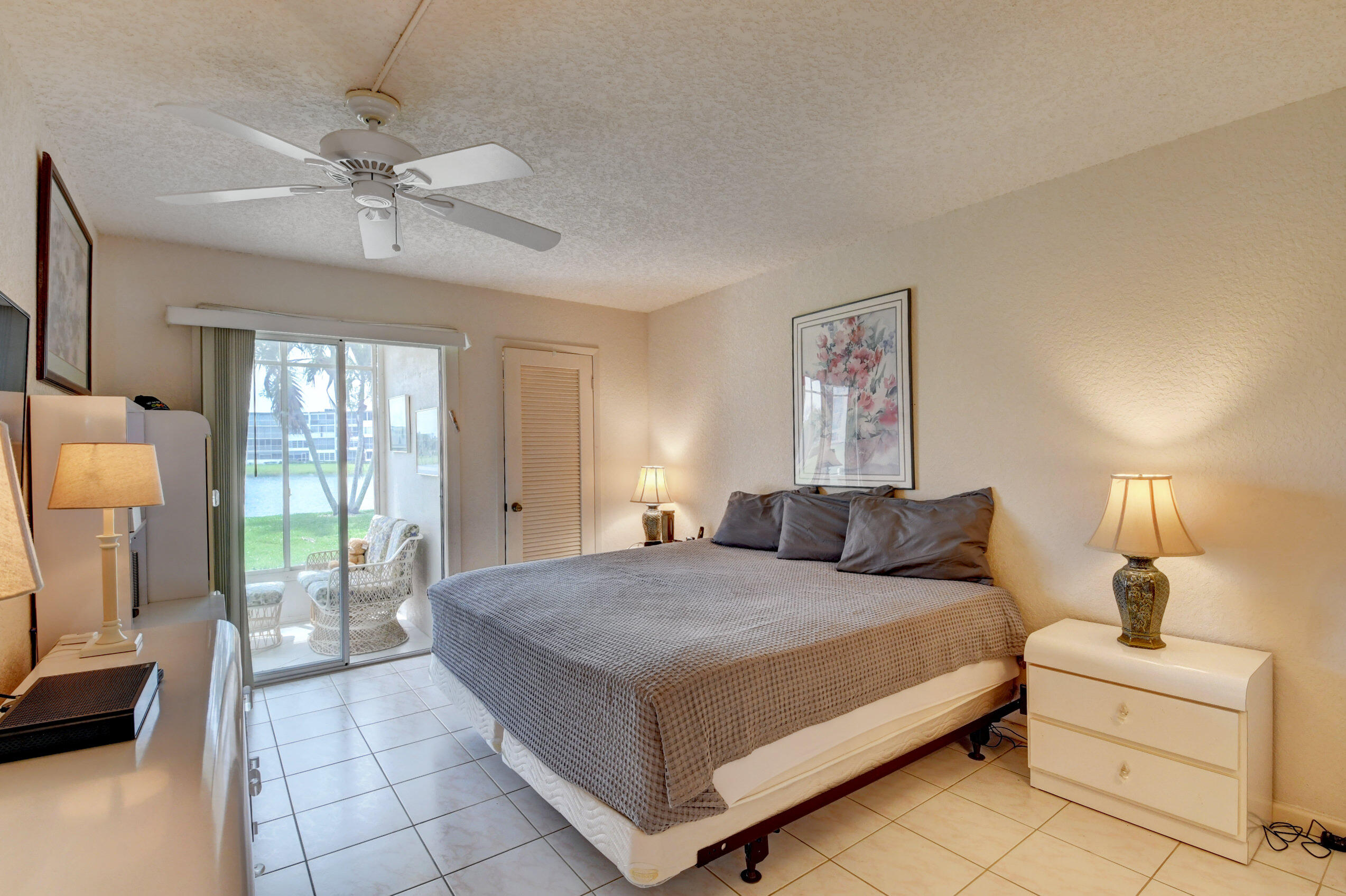 1045 Wolverton C, Unit 1045 Boca Raton, FL 33434 - Photo 18 of 67 a bedroom with a large bed and a chandelier