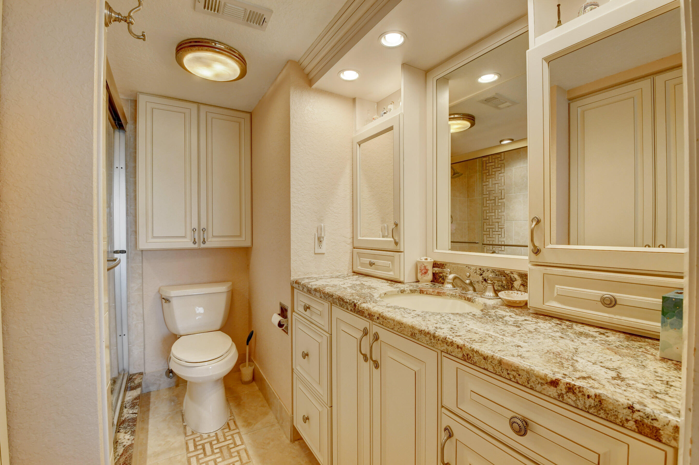 1045 Wolverton C, Unit 1045 Boca Raton, FL 33434 - Photo 21 of 67 a bathroom with a granite countertop sink a toilet and a mirror