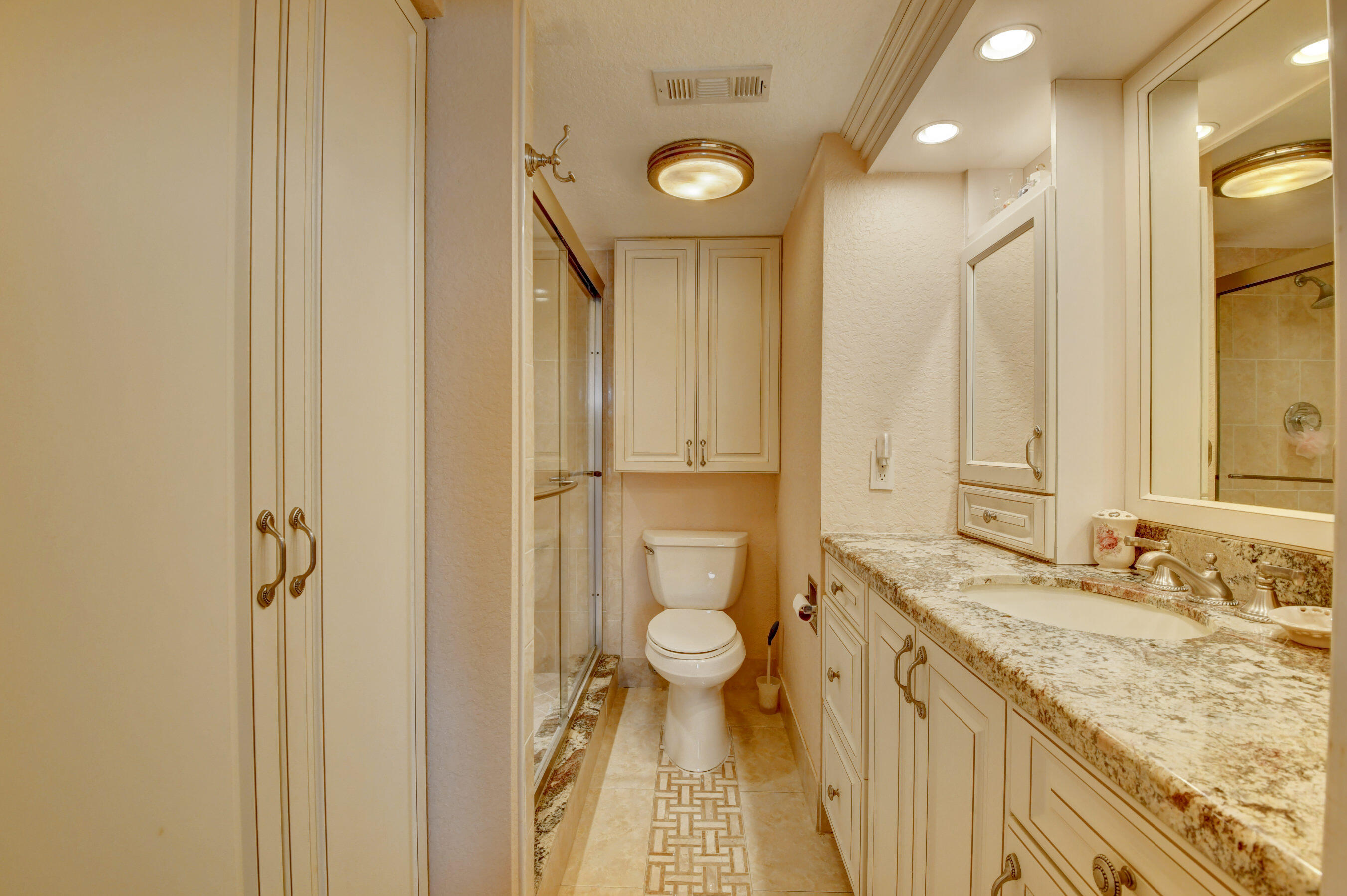 1045 Wolverton C, Unit 1045 Boca Raton, FL 33434 - Photo 22 of 67 a bathroom with a granite countertop sink toilet and shower