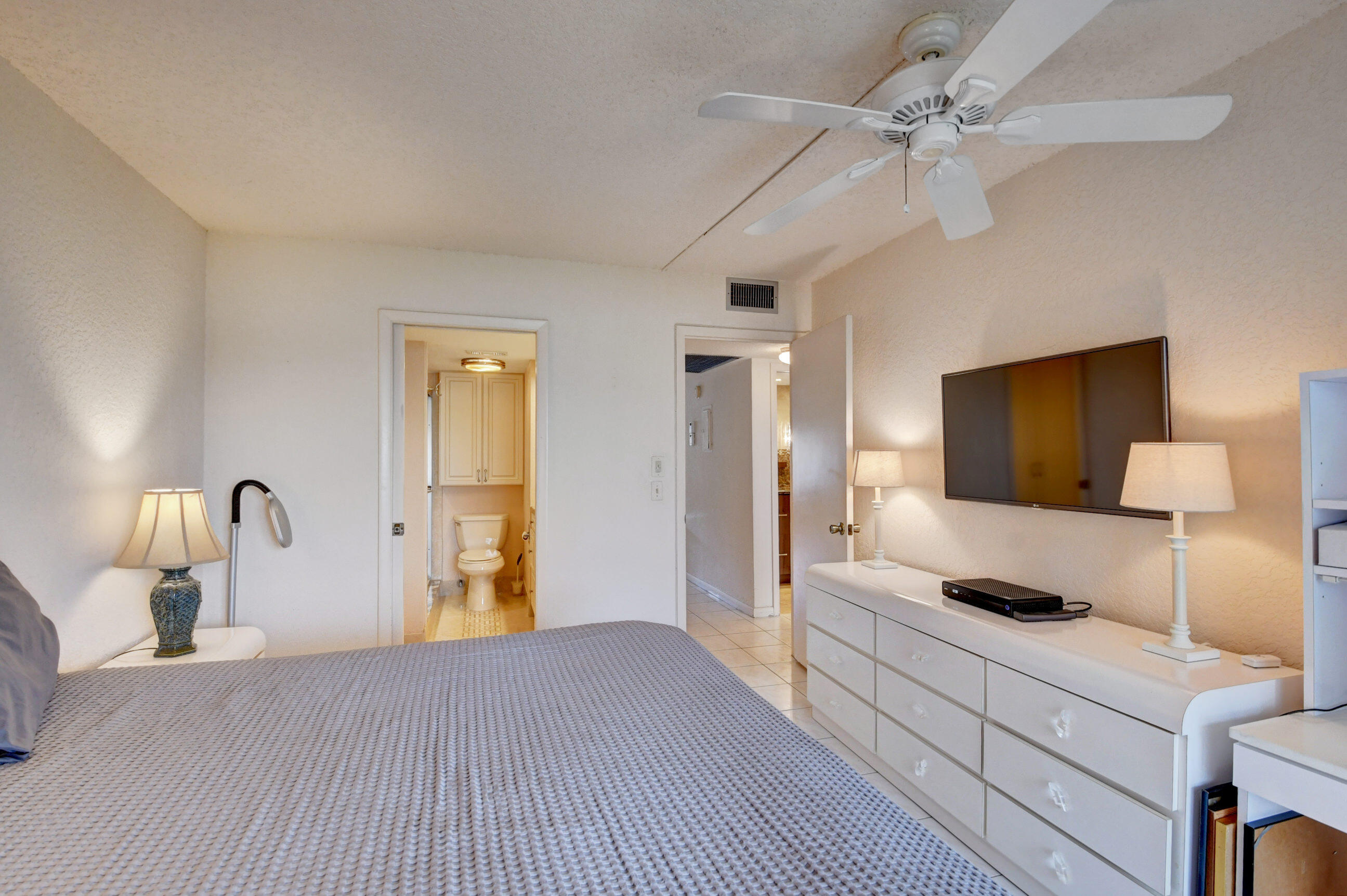 1045 Wolverton C, Unit 1045 Boca Raton, FL 33434 - Photo 24 of 67 a bedroom with a bed and a chandelier