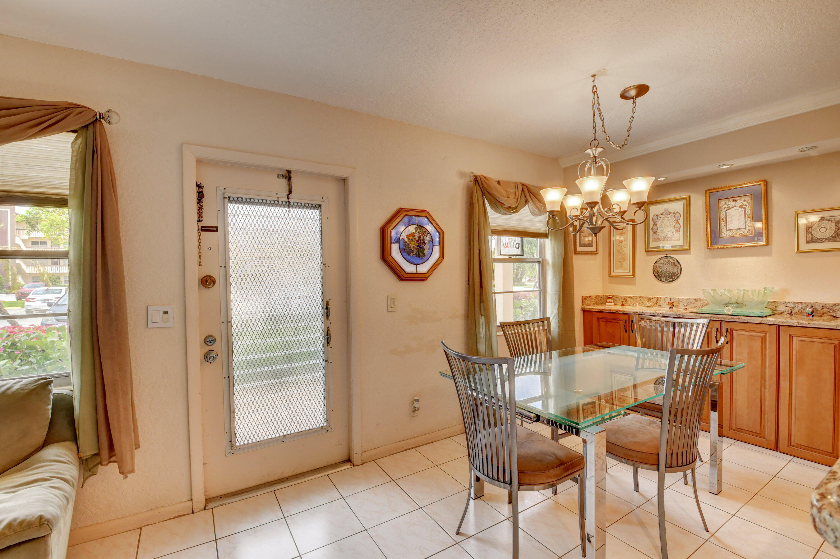 1045 Wolverton C, Unit 1045 Boca Raton, FL 33434 - Photo 9 of 67 a view of a dining room with furniture and a chandelier