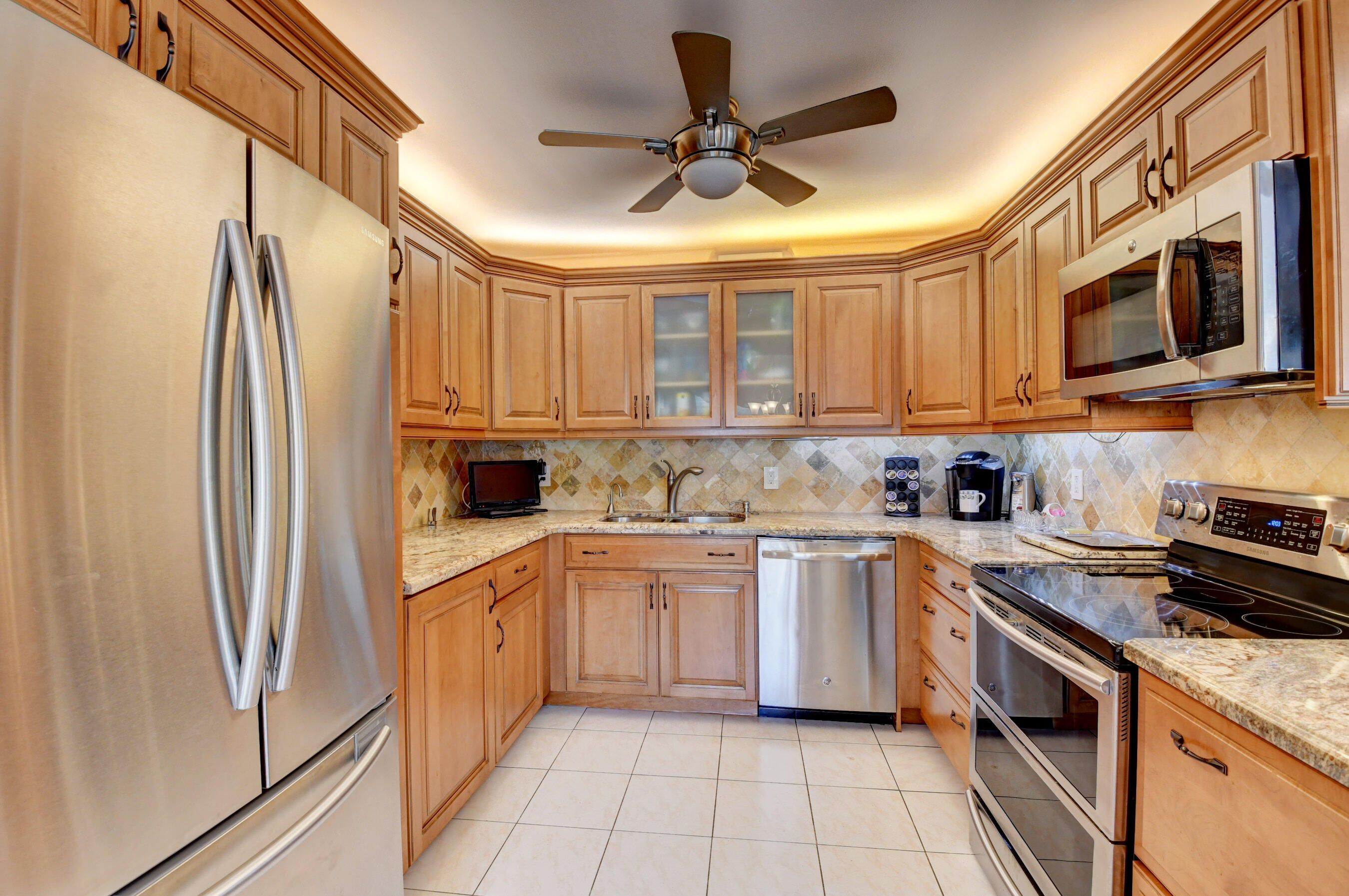 1045 Wolverton C, Unit 1045 Boca Raton, FL 33434 - Photo 10 of 67 a kitchen with stainless steel appliances granite countertop a refrigerator a sink dishwasher a stove and white cabinets with wooden floor