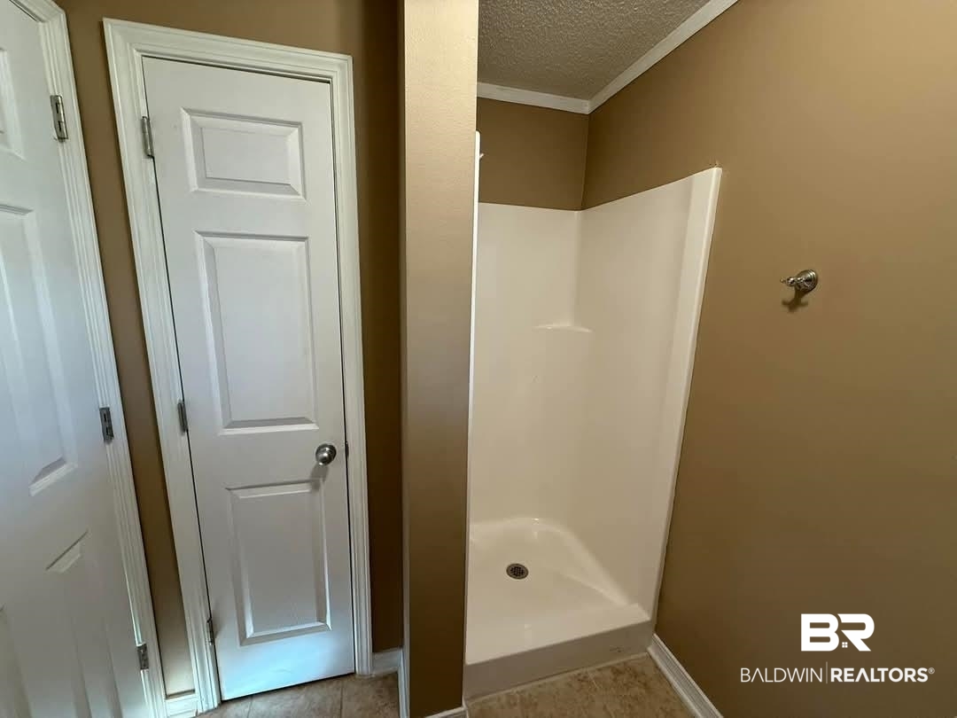 8912 Sherman Road Foley, AL 36535 - Photo 32 of 35 Bathroom with ornamental molding, a shower stall, a textured ceiling, and tile patterned floors