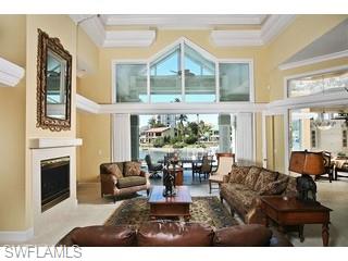 333 Devils Bight Naples, FL 34103 - Photo 3 of 8 a living room with furniture a fireplace and large windows