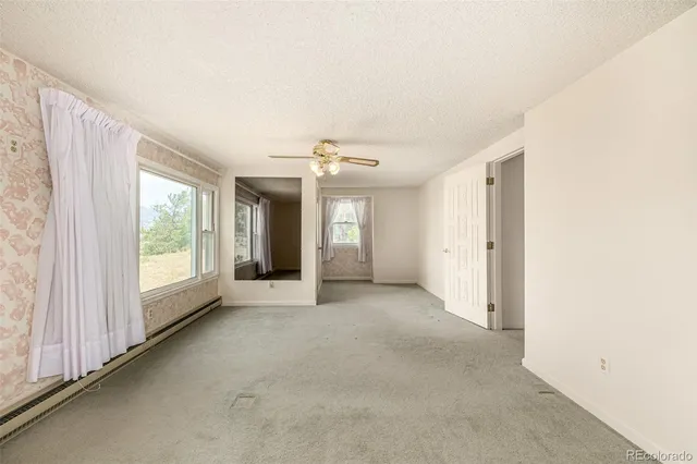 a view of a big room with windows and chandelier fan